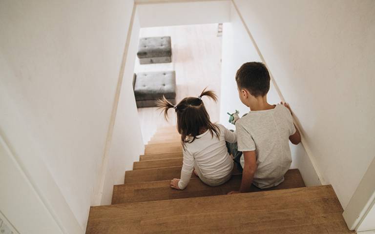Brother and sister playing on the stairs at home. Image by malysheva (Adobe Stock)