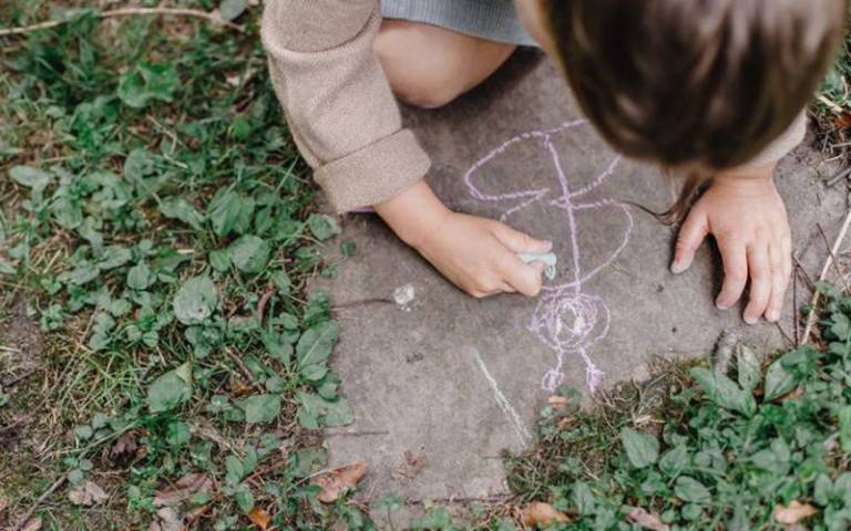 Child drawing a butterfly with chalk outdoors. Image: Allan Mas from Pexels.