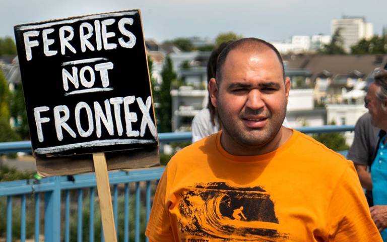 Man holds a sign reading 'ferries not Frontex' at immigration protest
