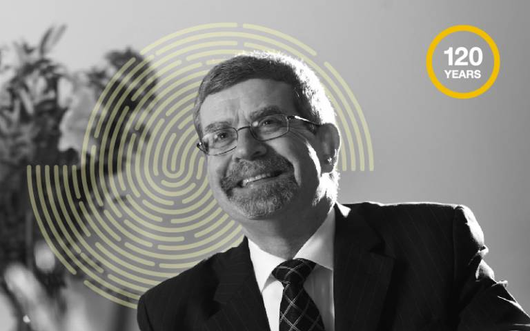 Image of Geoff Whitty in black and white with yellow fingerprint and 120 roundel. Photo Richard Lea-Hair for UCL.