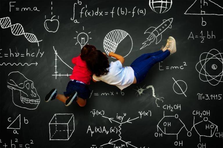 Girls writing on a blackboard with science subjects