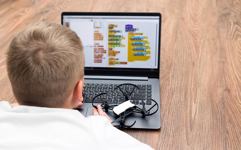 Boy using Scratch Maths on a laptop, with a small drone beside him