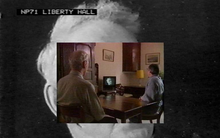 Screenshot of a film, with two men watching a television. Image Credit: Emanual Almborg.