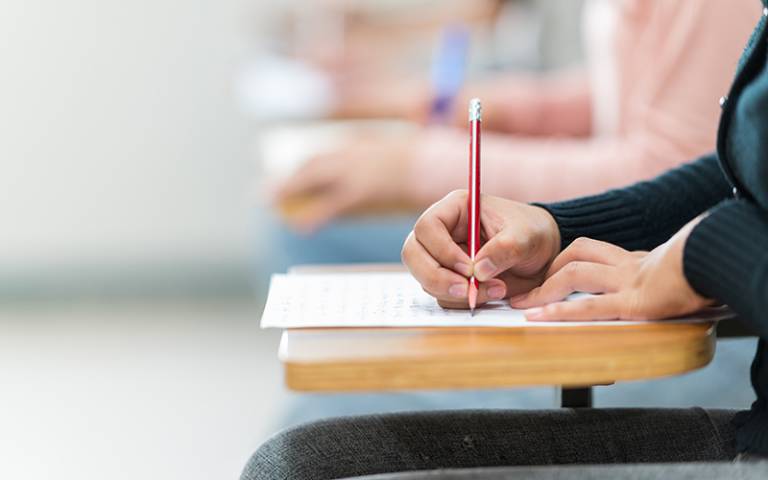 Students sit for exams at the desks in the classroom. Image: mnirat / Adobe Stock.