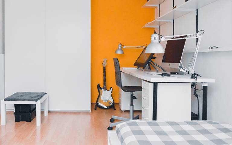 Student room with a bed, desk and computer. Image: Norbert Levajsics via Unsplash