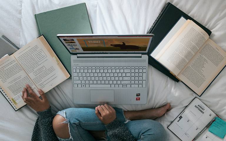 Student working at home surrounded by laptop and books. Image: Windows via Unsplash