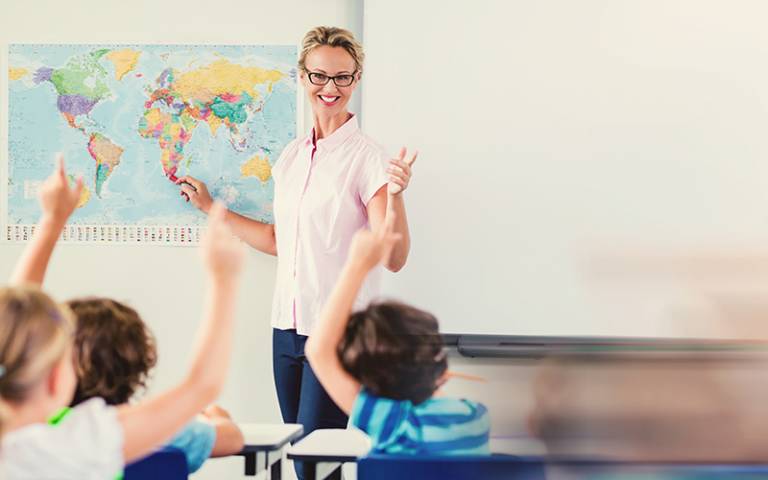 Teacher teaching kids in classroom. Image by vectorfusionart / Adobe Stock.
