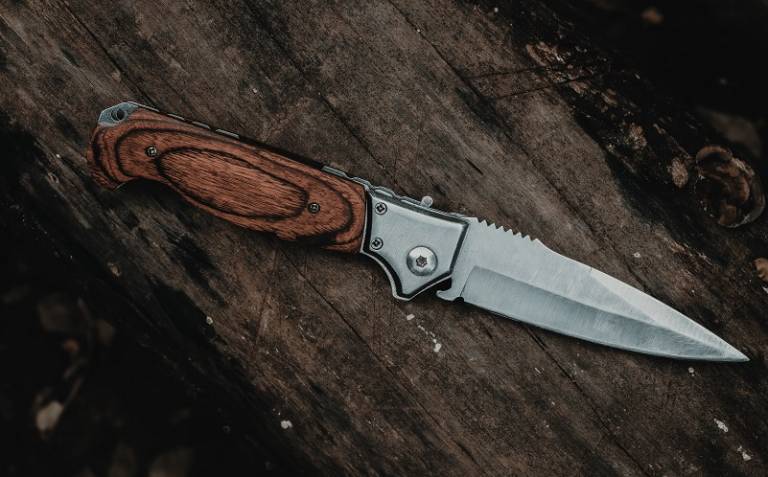 Knife with brown handle placed on top of wooden surface