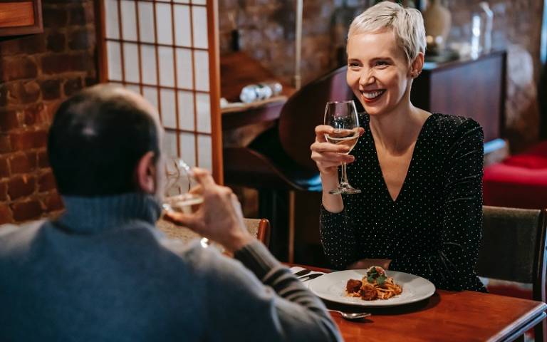 Man and woman sat at a table in a restaurant drinking wine