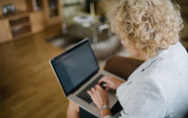 White middle aged woman with curly hair typing on laptop