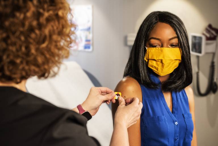 Nurse placing sticker on patient following vaccination
