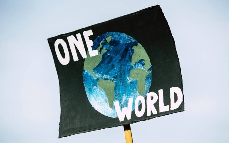 Sign saying 'One World' with image of earth on black background
