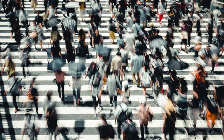 People walking on a busy street. The photo is blurry. Image: beeboys via Adobe Stock.