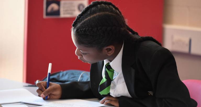 Secondary school pupil writing in an exercise book in class