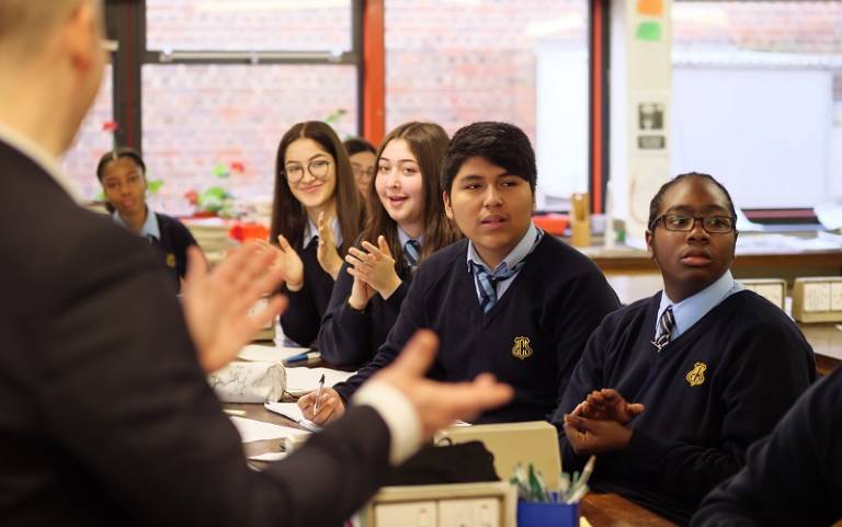 Secondary school pupils sat at front of class applauding