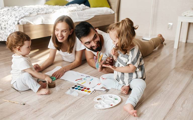 Smiling family making hand print with colours. Image by the faces / Adobe Stock.