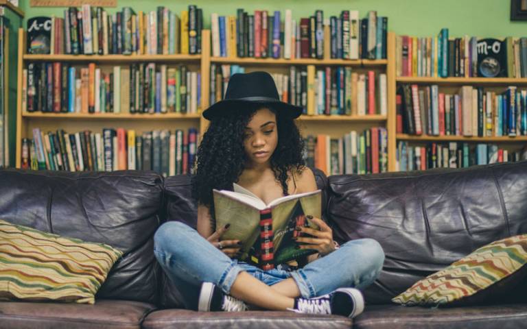 Teenager reading a book on a sofa
