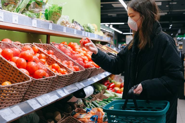 Woman wearing face mask shopping for tomatoes in supermarket. Image: Anna Shvets from Pexels