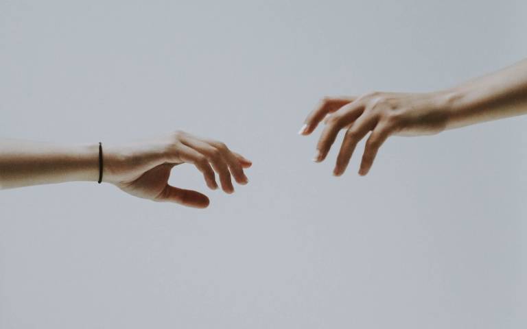 Two hands reaching out towards each other. Image: fotografierende via Pexels
