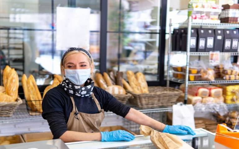 A female service worker selling bread in a mask