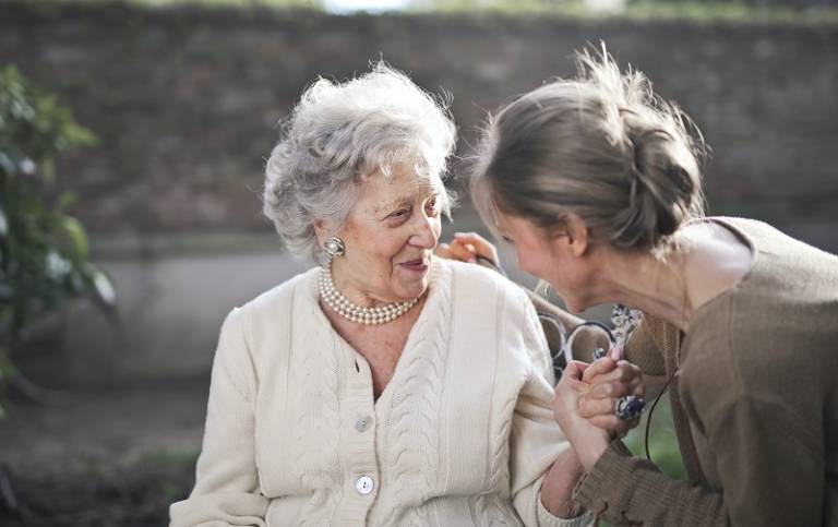 Woman speaking to elderly mother outside
