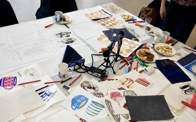 A table with scattered pieces of paper, art supplies, microphones, tea and mugs. Credit: Jonathan Hogg, Output Arts.
