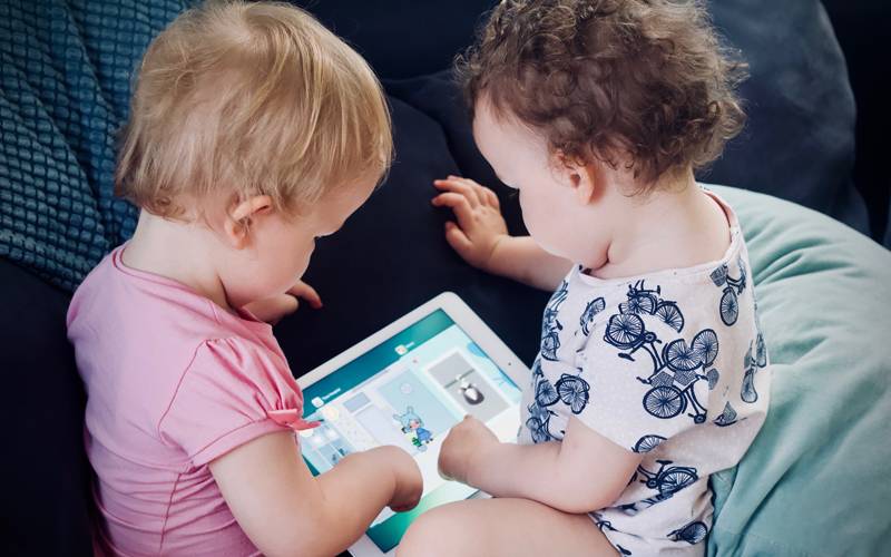 Two children sitting together and playing on iPad. Image: Jelleke Vanooteghem via Unsplash