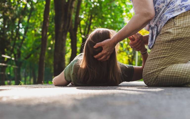 woman fainting on the ground with head supported