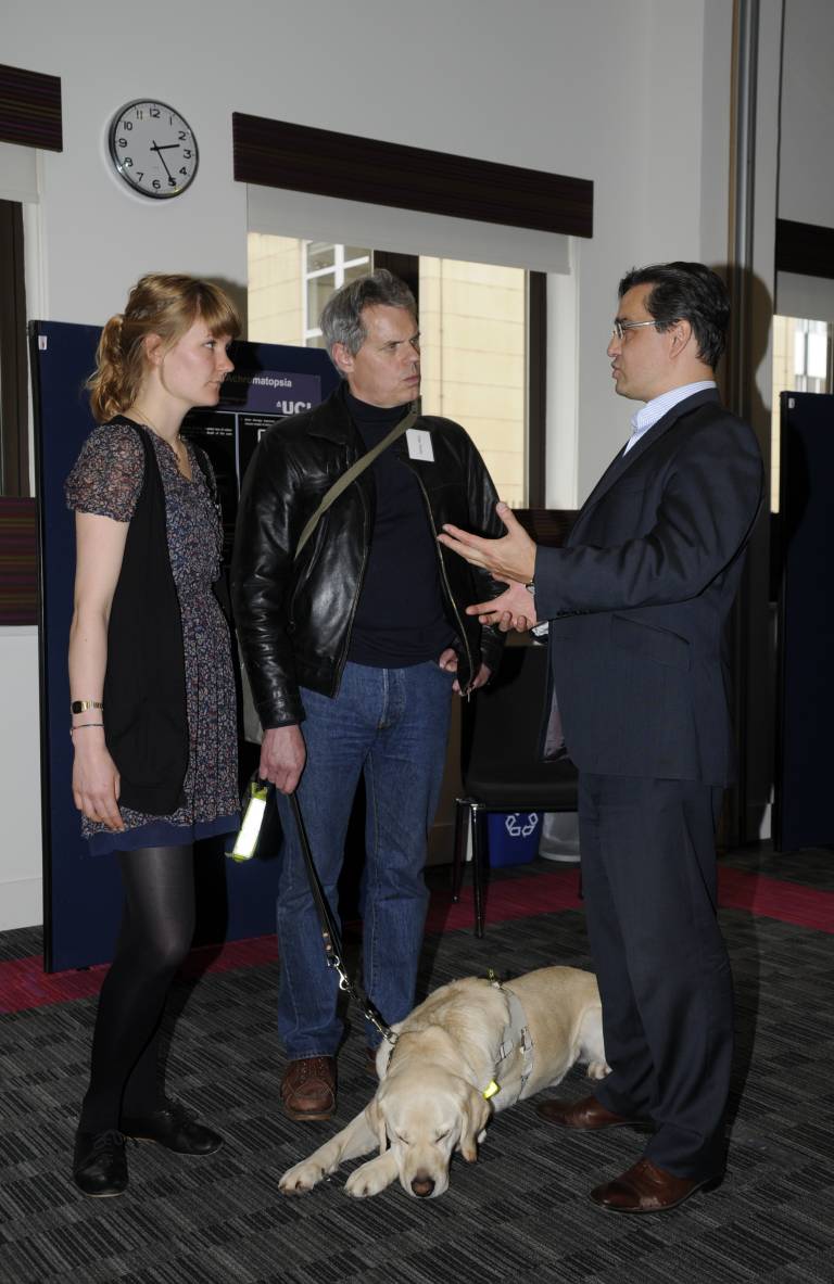 Prof Robin Ali and PhD student Sofia kline-Holthaus talking to a man with a guide dog