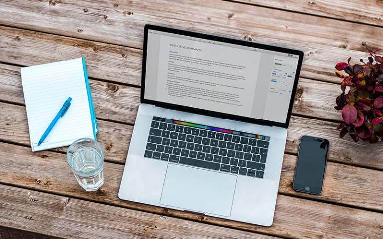 Picture of a laptop, notepad, mobile phone and a glass of water