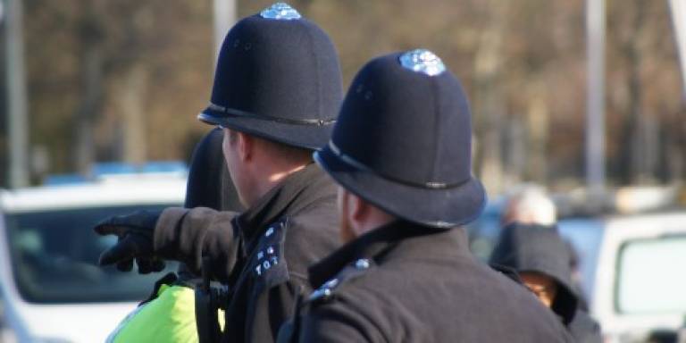 Two police men with black hats on and one pointing