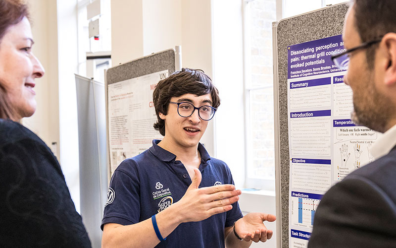A student standing in front of his research poster, talking
