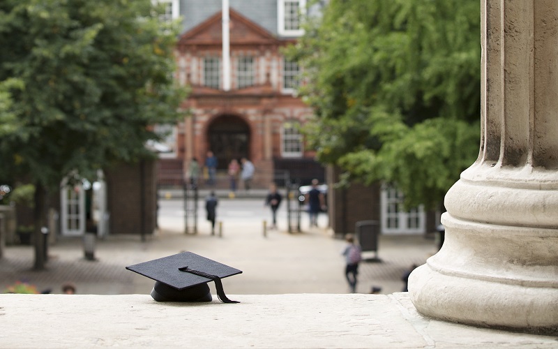 Mortar board on the steps of the UCL Portico building with Cruciform building in the background 