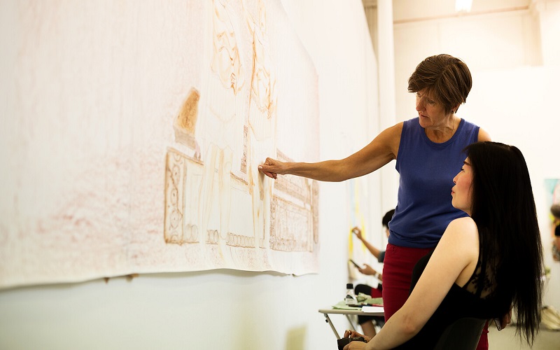 Student and teacher discussing artwork in studio