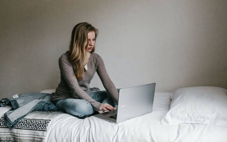Girl sat on bed using laptop