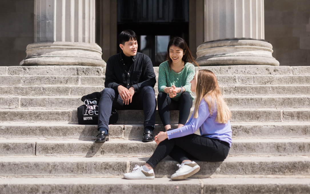 UPC students sitting on the stone steps in front of the portico
