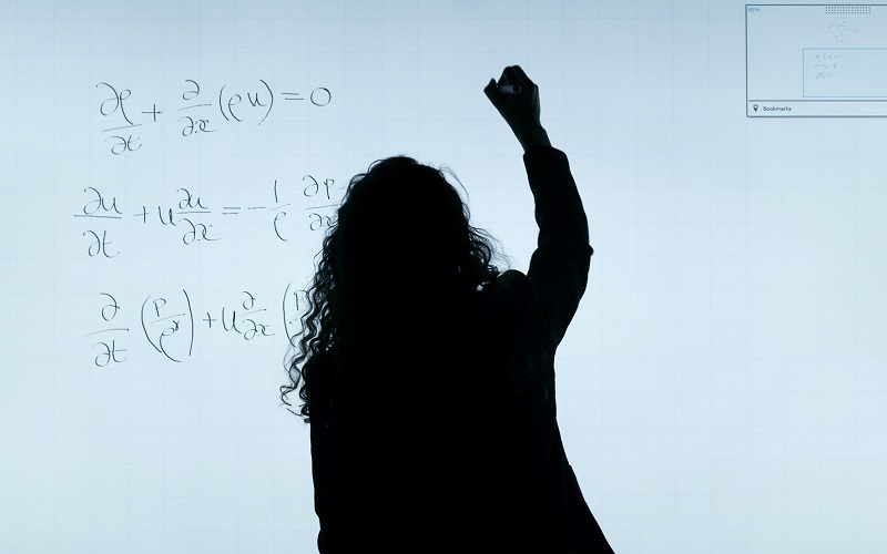 Woman writing maths equations on a board
