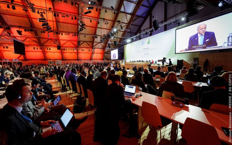 A large room with people sitting in rows looking at a screen at COP21 in Paris