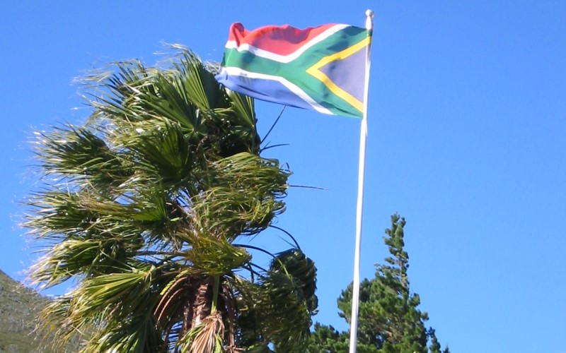 The flag of South Africa in front of trees and a blue sky