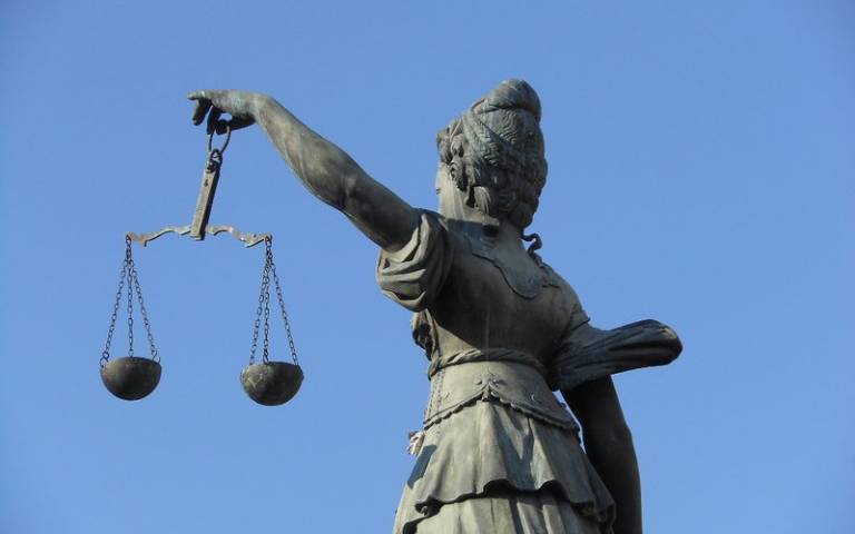 A grey statue of Lady Justice holding scales