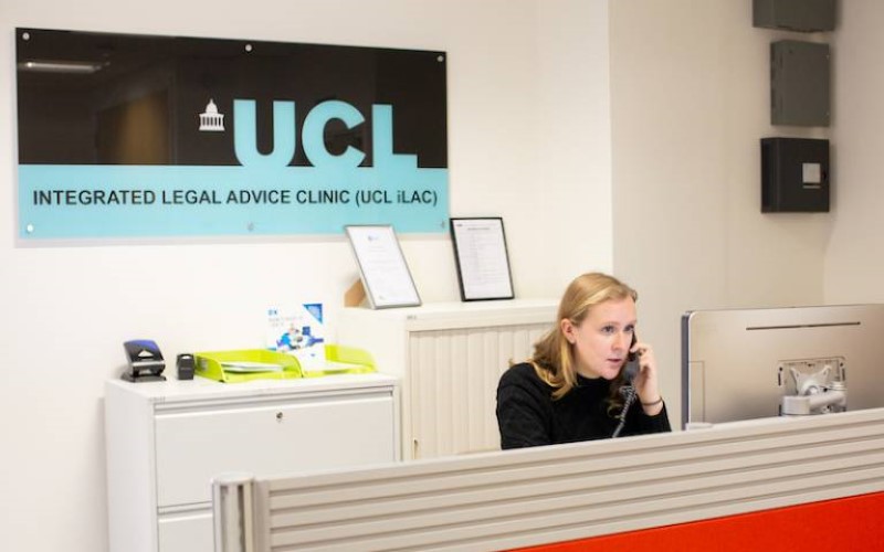 A person sitting at a reception desk and answering the phone. Behind her, is a sign which says 