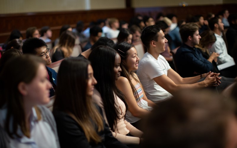 A row of students sitting together and smiling at the 2019 new students induction