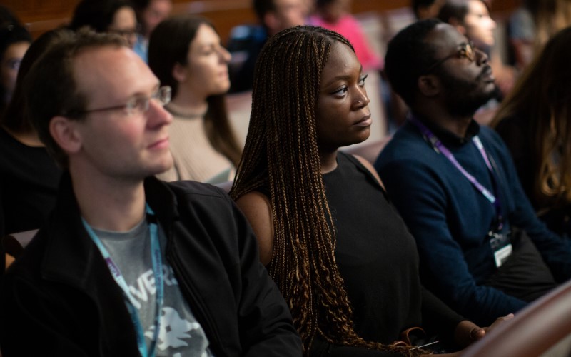 Three students sitting in a row listening to a talk at the LLM induction 2019