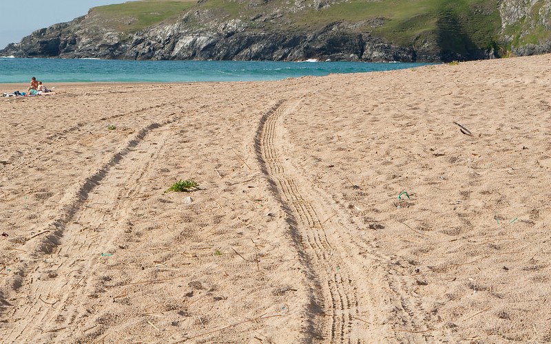 Holywell Bay beach. Tire tracks in the sand.