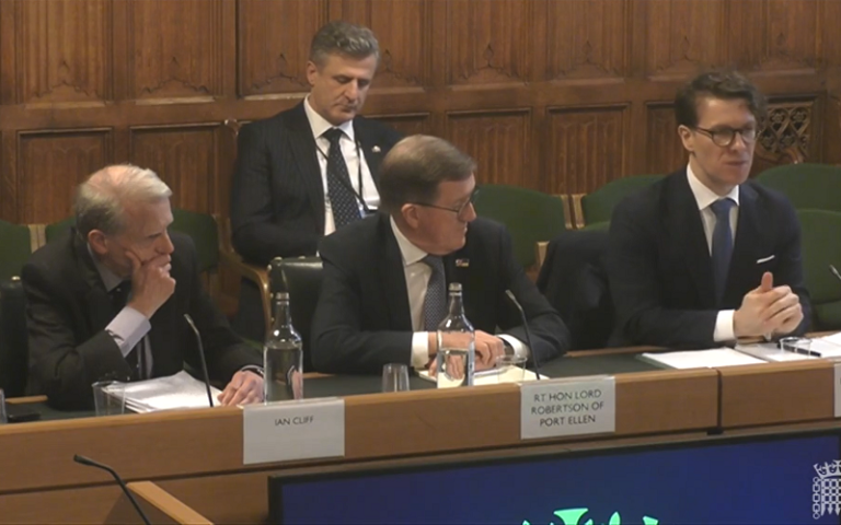 Dr Hoxhaj OBE giving evidence in front of the Foreign Affairs Select Committee. He is sitting at a desk next to The Rt Hon. the Lord Robertson of Port Ellen KT and Ian Cliff OBE 