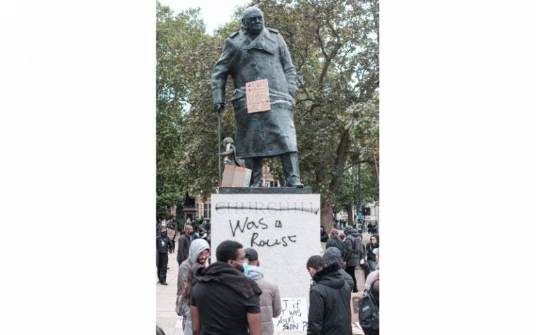 A statue of Winston Churchill on a plinth daubed with the words "was a racist"