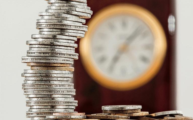 Image of a stack of coins with a clock in the background
