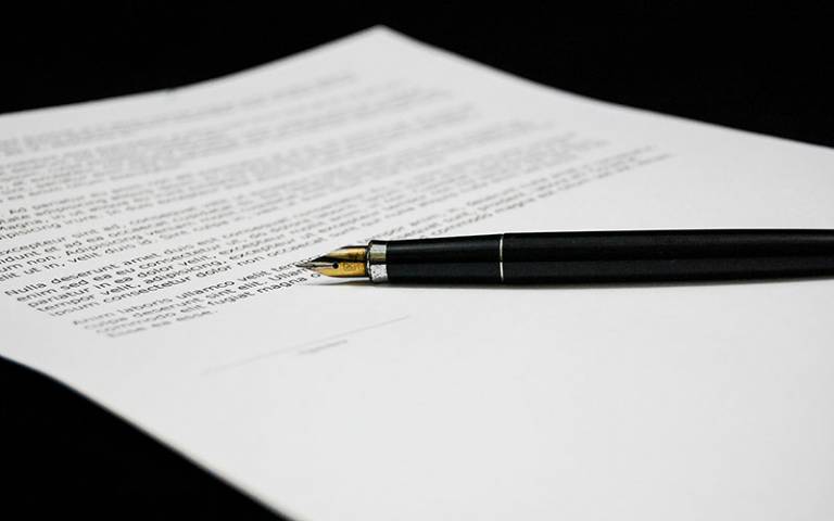 Image of a document and pen in hand