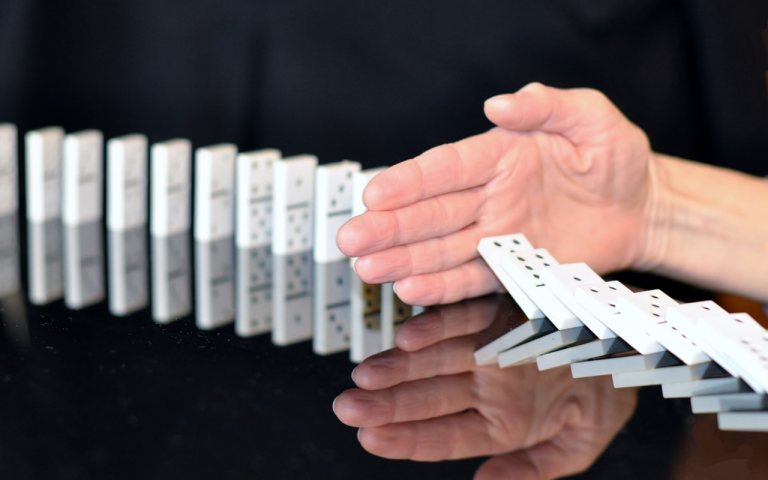 Image of a hand imbetween a line of dominoes