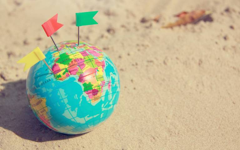 small globe on a beach with flags stuck in it